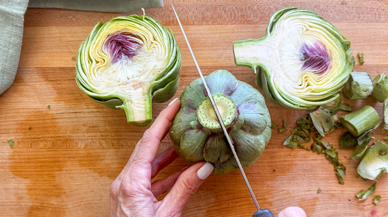 hand cutting artichoke in half