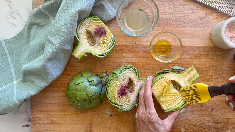 hand brushing artichoke halves