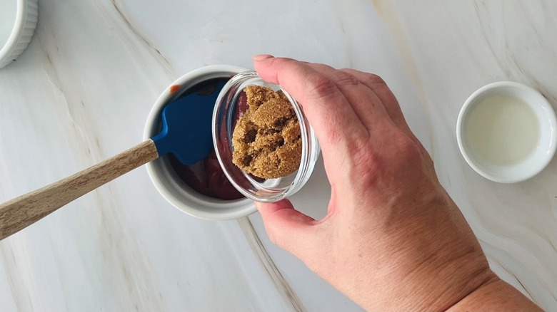 hand adding sugar to sauce