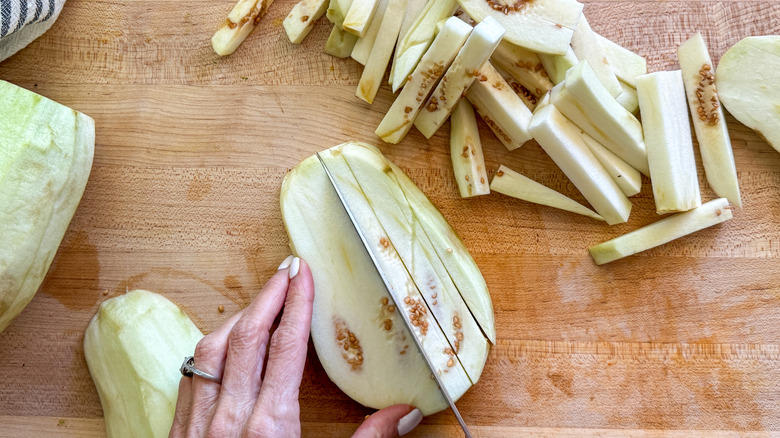 hand slicing eggplant on board