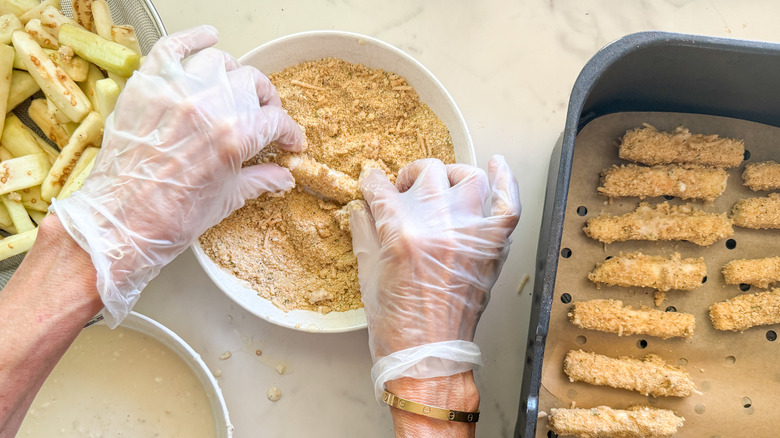 hands rolling eggplant in dry mixture