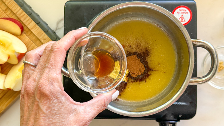 hand adding vanilla to pot