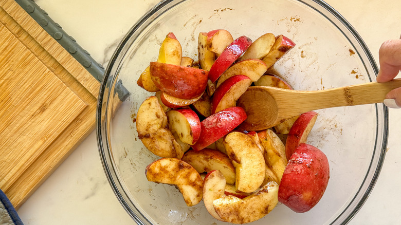 hand stirring apples in bowl