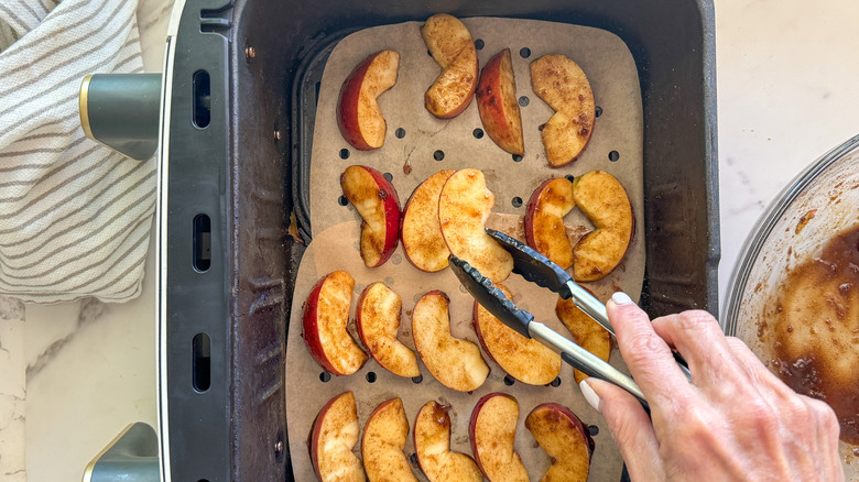 tongs placing apple in fryer