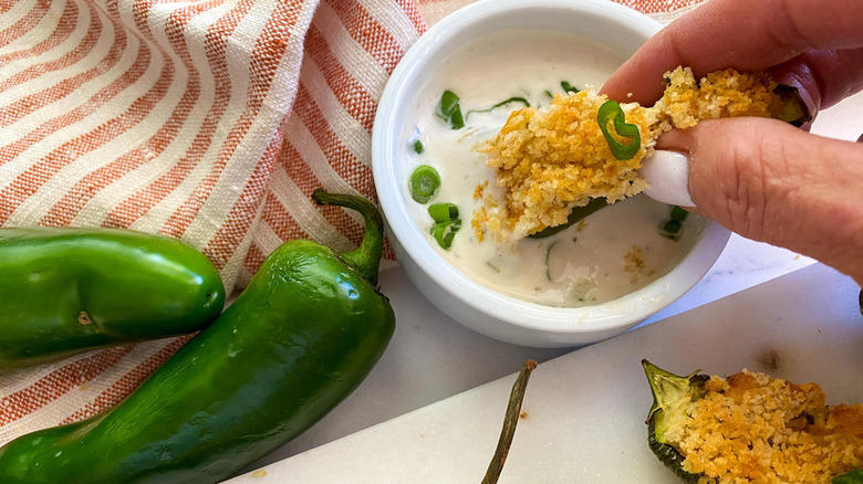 hand dipping jalapeno popper in sauce