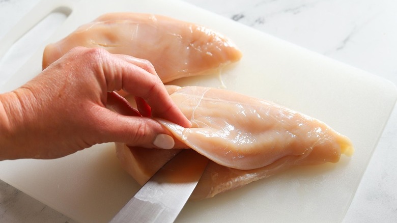 knife slicing open raw chicken