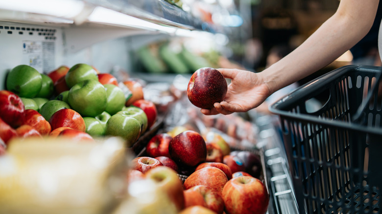 Person picking apples out of produce aisle