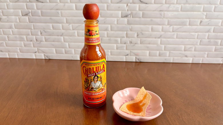 Cholula sweet habanero hot sauce bottle next to tortilla chip