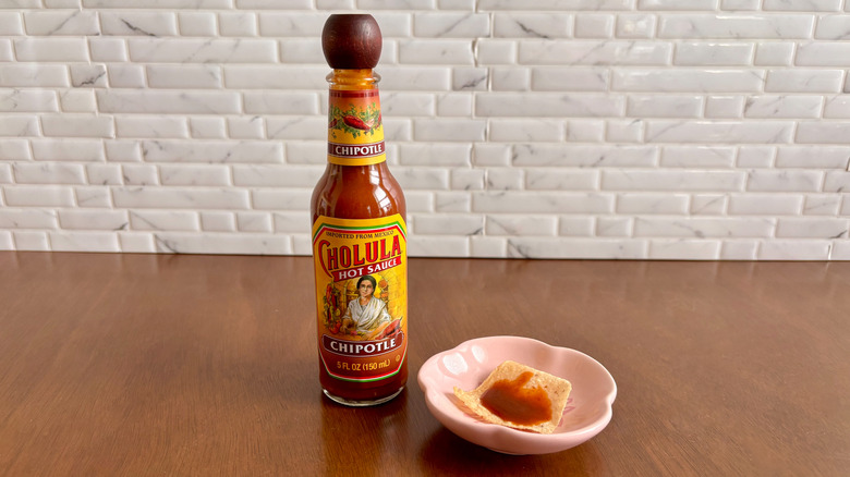 Cholula chipotle hot sauce bottle next to tortilla chip