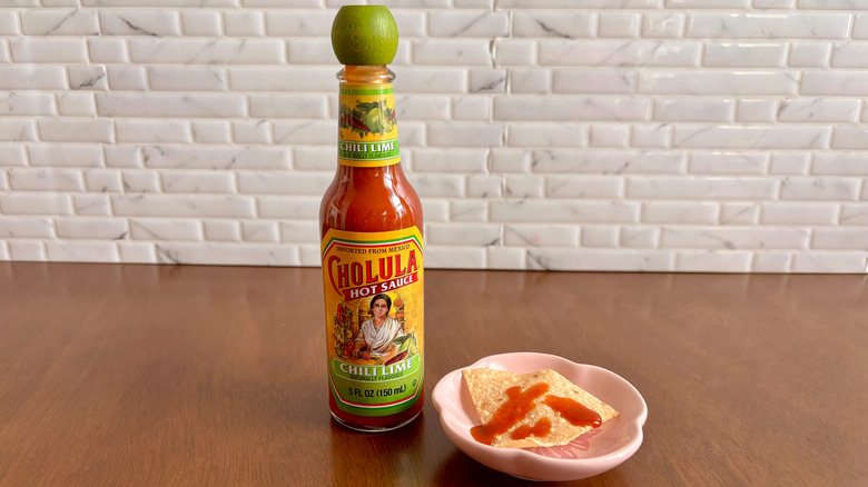 Cholula chili lime hot sauce bottle next to tortilla chip