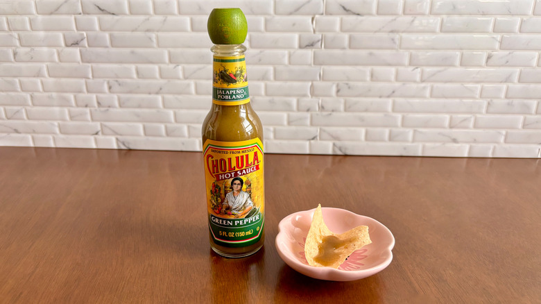 Cholula green pepper hot sauce next to tortilla chip