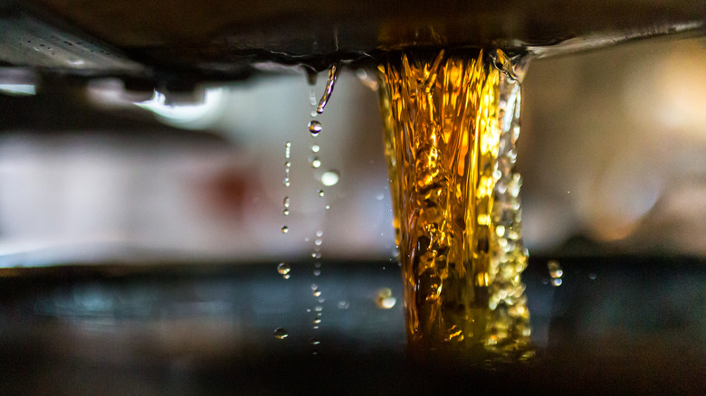 Dark liquor pouring from barrel.