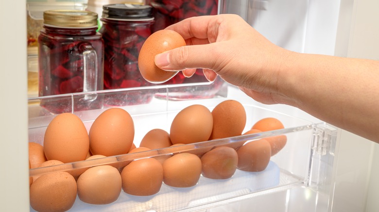 person grabbing eggs from refrigerator