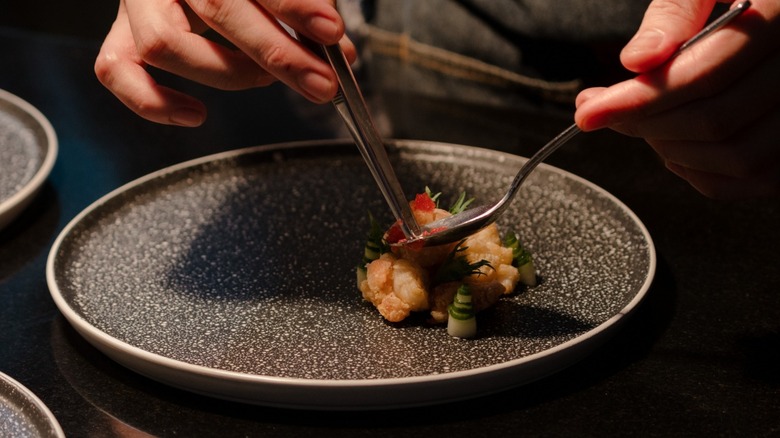 Close-up image of chef's hands plating food 