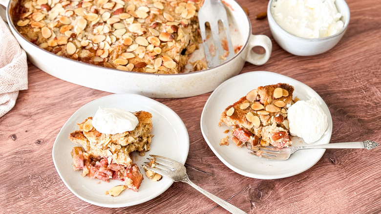 Almond-rhubarb from scratch dump cake slices on plates with almond whipped cream on table