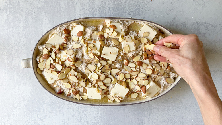 Sprinkling sliced almonds on top of unbaked almond-rhubarb dump cake