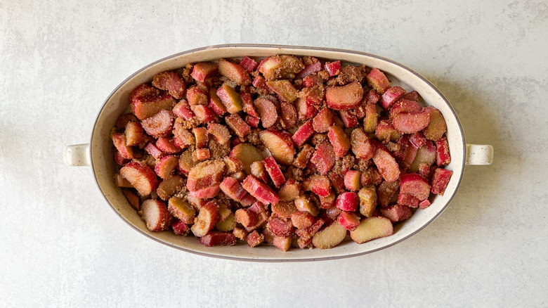 Rhubarb tossed with brown sugar and cinnamon in large oval baking dish