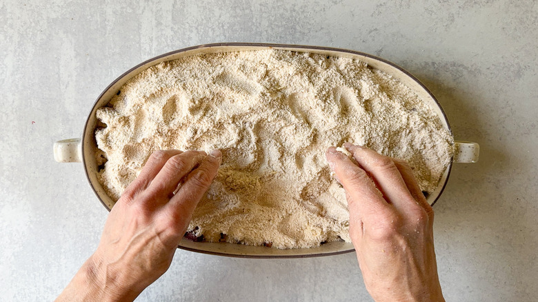 Spreading homemade cake mix over rhubarb for almond-rhubarb dump cake