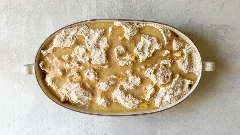 Melted butter on top of almond-rhubarb dump cake ingredients in baking dish