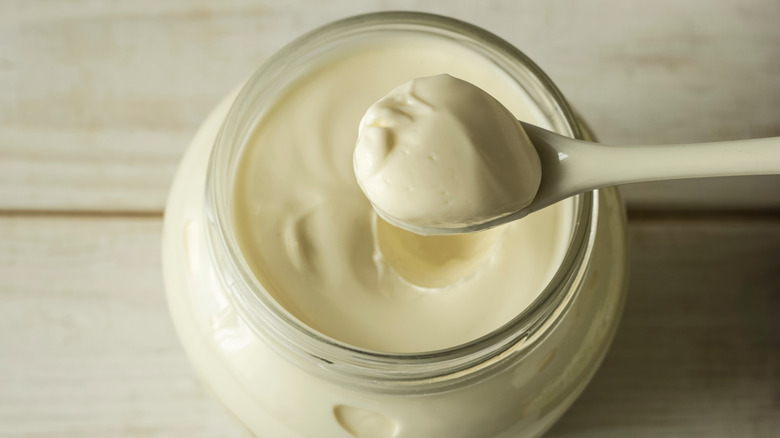 Scooping mayonnaise on wooden background