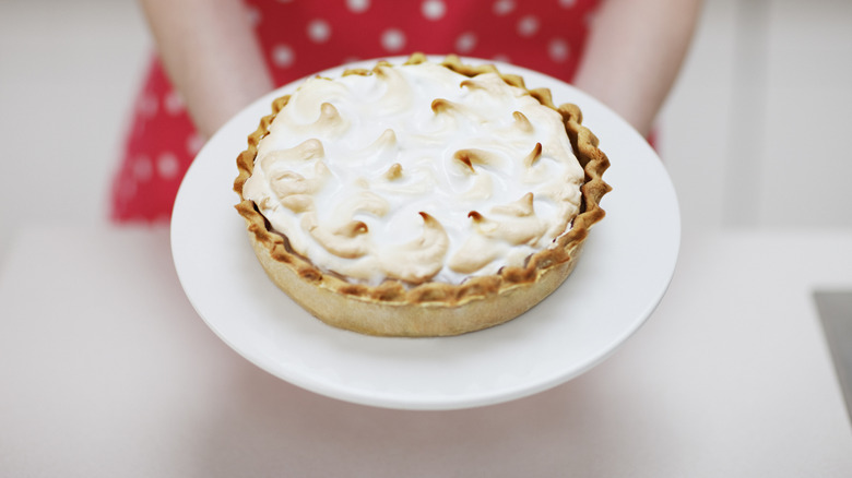 pie topped with meringue on plate held by person in polka dot dress