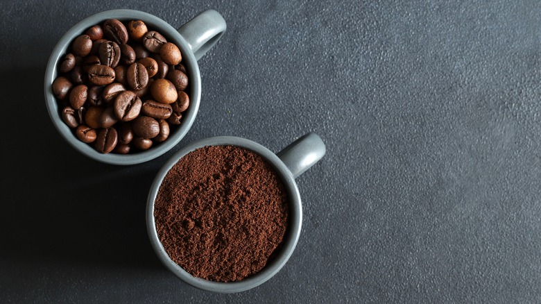 A mug of coffee beans and a mug of coffee grounds