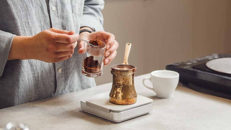 Hands using a scale to measure coffee grounds for Turkish coffee