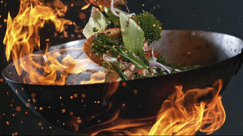 Wok tossing food over flames