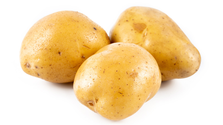 three golden potatoes on a white background