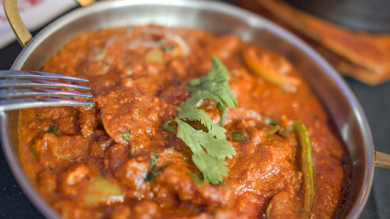 A fork hovers over a bowl of tikka masala