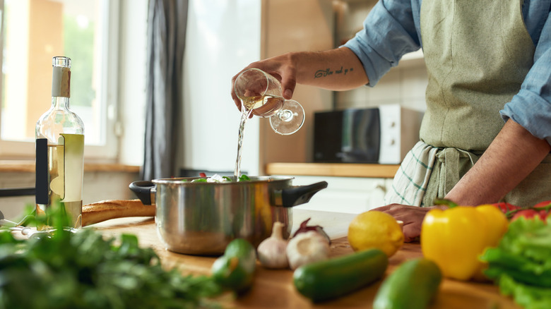 A person pours wine into a pan.