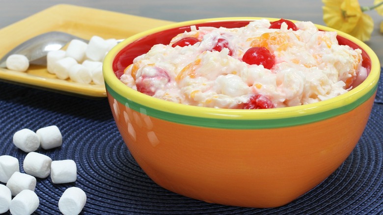 Ambrosia salad in an orange bowl next to marshmallows