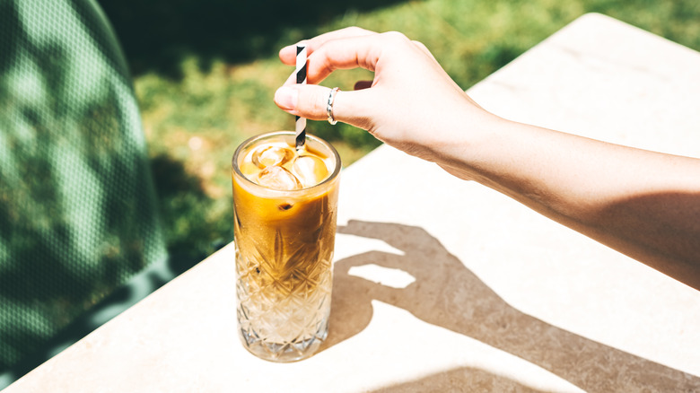 Hands holding glass of iced coffee