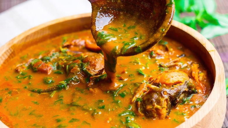 Ladle lifting up soup from wooden bowl