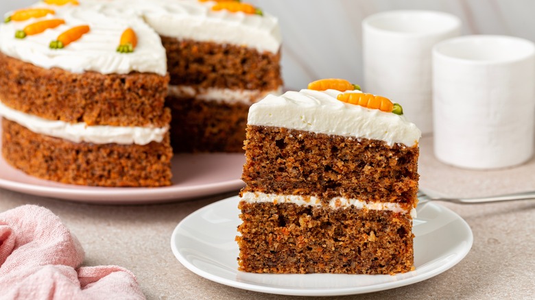 Whole carrot cake with slice on plate