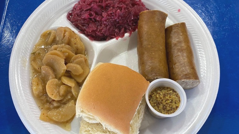 sausage, cabbage, potatoes, and rolls on a plate