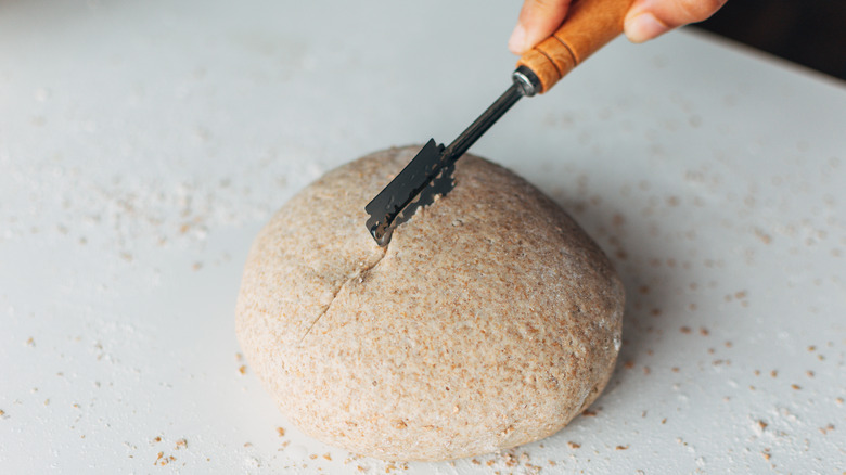 person scoring bread dough