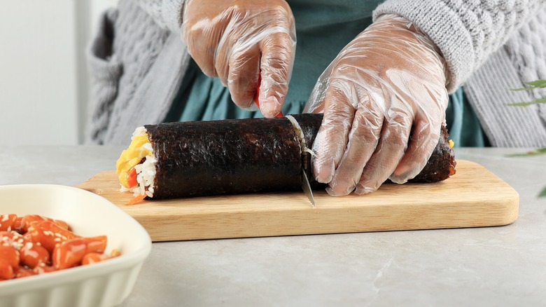 Hands cutting kimbap roll 