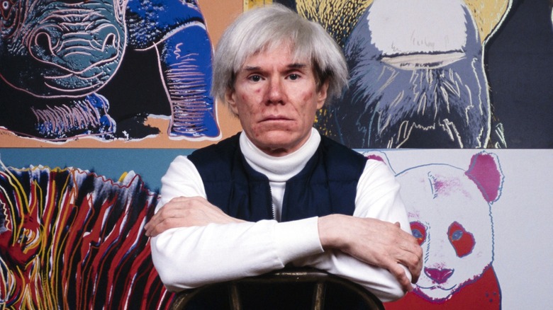 Andy Warhol in front of his art