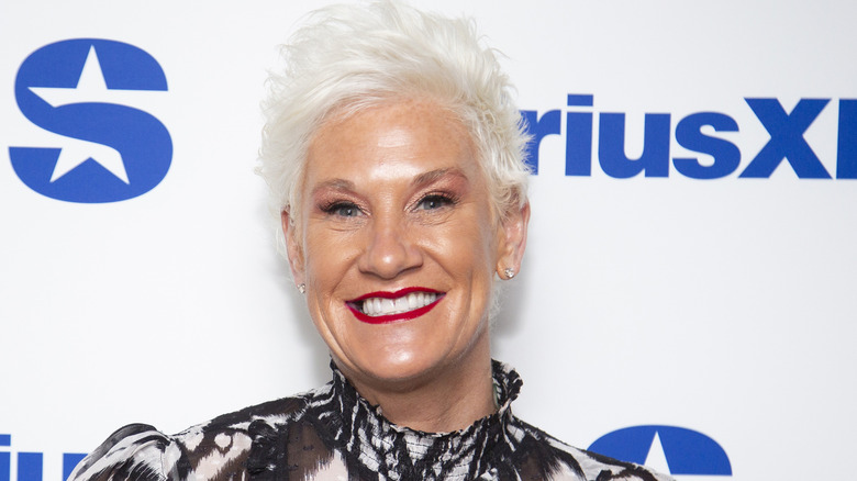 Anne Burrell smiling with red lipstick and printed shirt