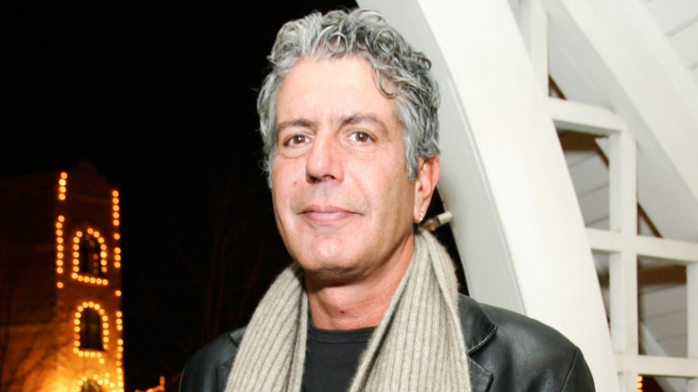 Anthony Bourdain smiles in black jacket and beige scarf