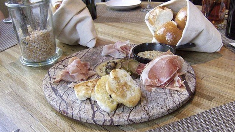 A Husk charcuterie plate with rolls on a dinner table