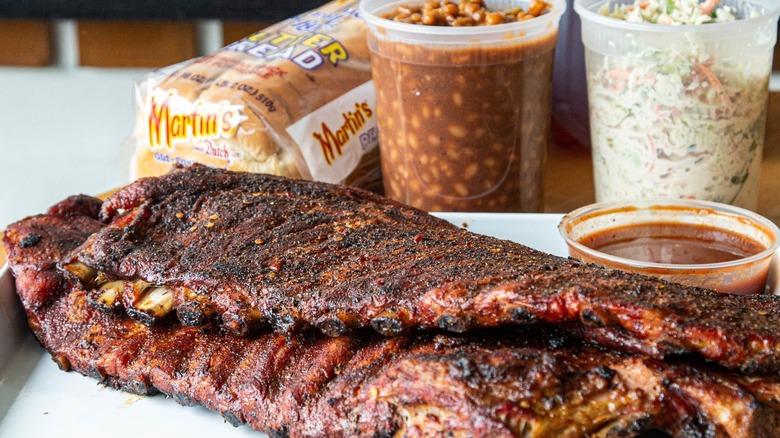 BBQ ribs, bread, and plastic containers of sides