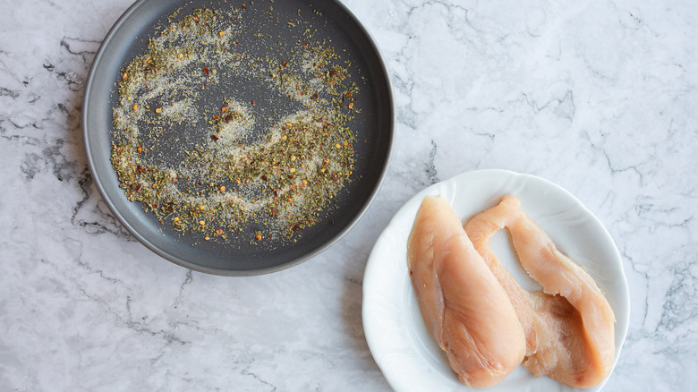 Plate with spices alongside chicken breasts