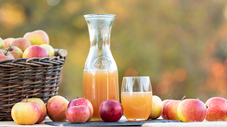 fresh apple cider next to whole apples