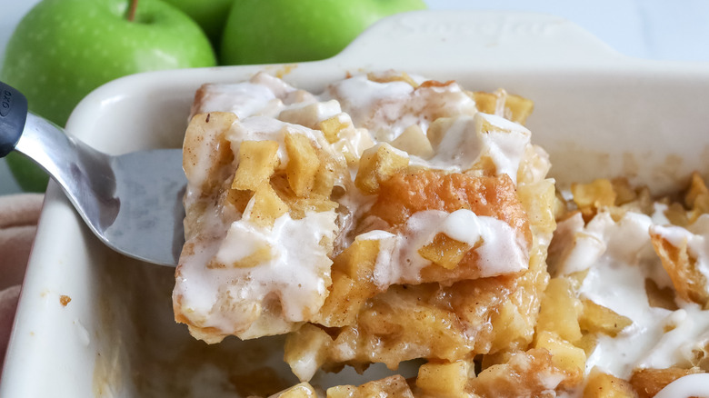 a slice of apple fritter breakfast casserole being cut out of the casserole dish