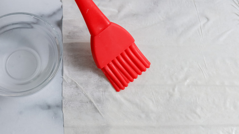 phyllo on a table being brushed with water