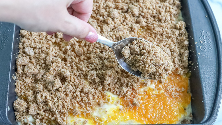 hand sprinkling streusel on cake