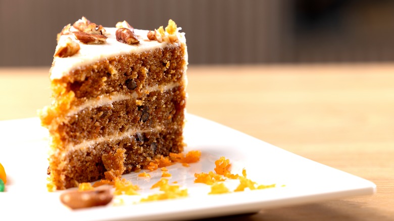 Slice of carrot cake on white plate with grated orange zest