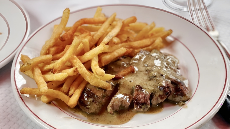 Steak frites dish with fries and sauce-covered steak